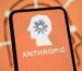 The Anthropic logo is displayed on the screen of a smartphone with the company's branding in the background.