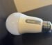 A Govee smart bulb lies on a black bookshelf.