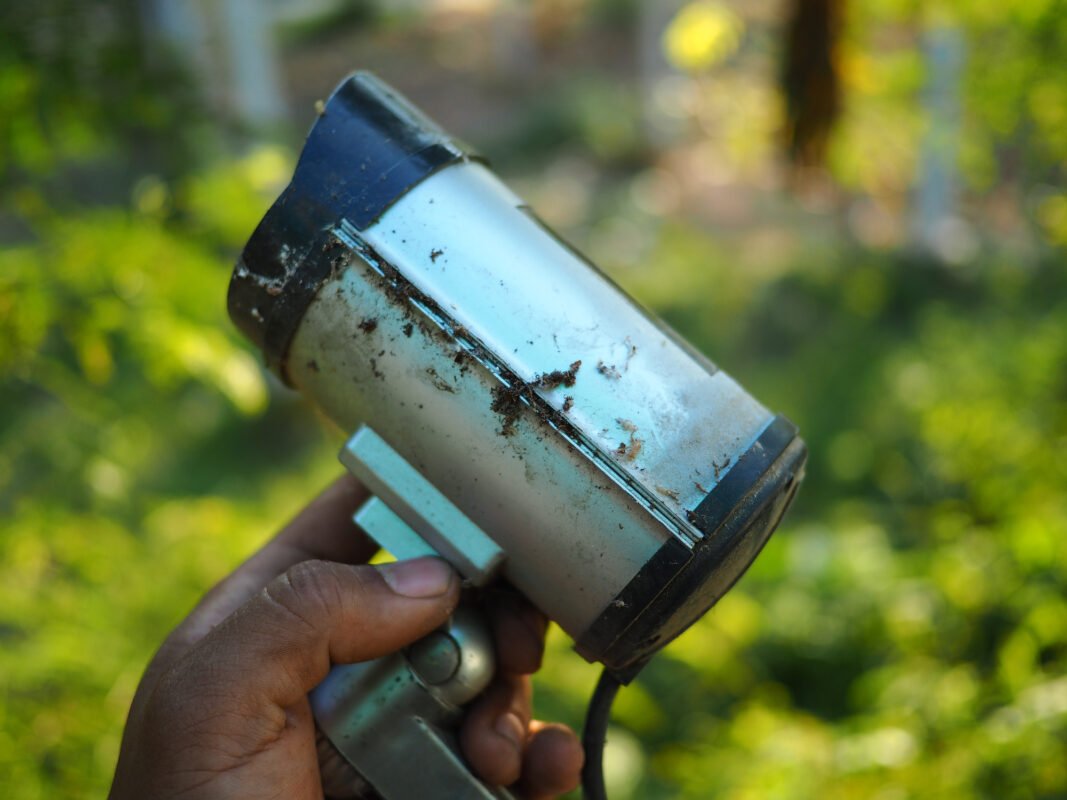 A hand holds an old damaged security camera.