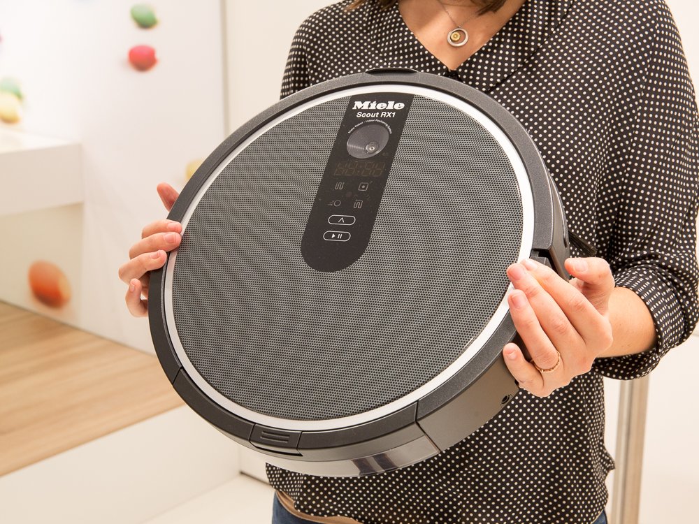 Hands hold a robot vacuum.