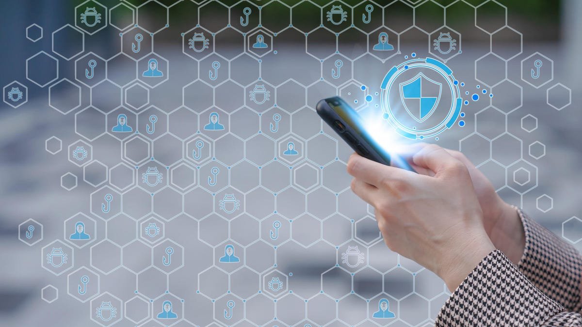 A person uses a phone against an illustration of security icons forming a shield.